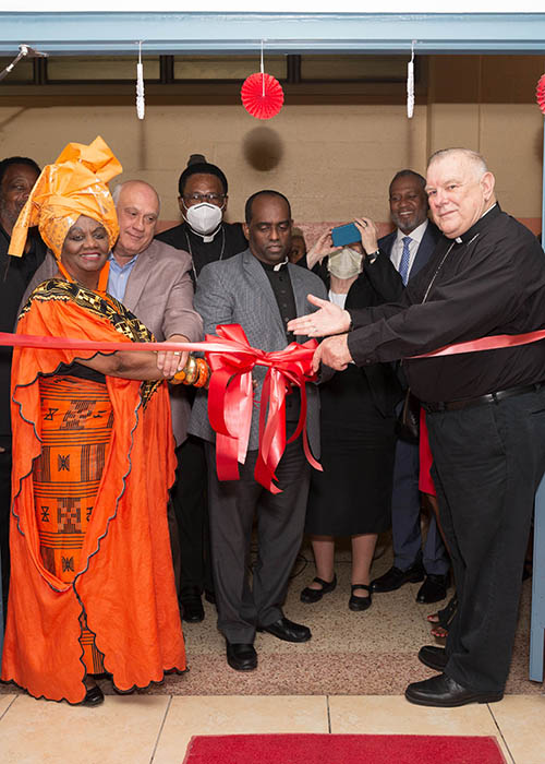 Archbishop Thomas Wenski leads a July 21, 2021 blessing and ribbon-cutting of a new community computer literacy center at Notre Dame d'Haiti Mission in Miami. With him are, left, Dorothy Bendross-Mindingall, former Democratic member of the Florida House of Representatives and a District 2 Board Member of Miami Dade County Public Schools, and Father Reginald Jean-Mary, center, administrator of Notre Dame d'Haiti.
