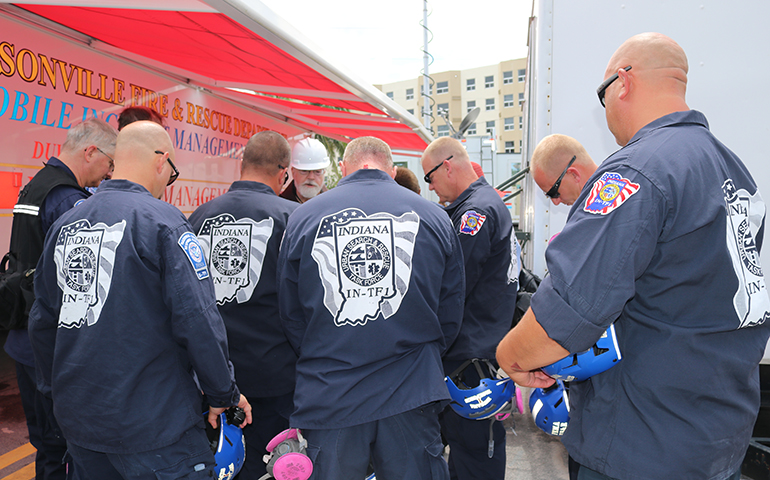 Boston Cardinal Sean Patrick O’Malley prays with members of an Indiana search and rescue team during a July 2, 2021 visit to the site of the partially collapsed Champlain Towers South condominium.