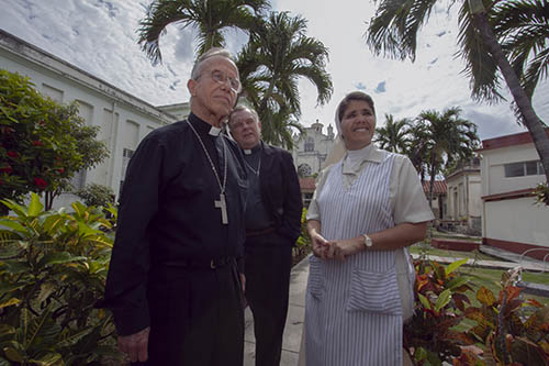 Durante una visita de la Orden de Malta en el 2011, el entonces Obispo Auxiliar de La Habana, Mons. Alfredo Petit, el Arzobispo Thomas Wenski y la Hermana Nadiezca Almeida de las Hijas de la Caridad de San Vicente de Paúl, caminan por el patio del hogar para ancianas en los terrenos de la Parroquia San Francisco de Paula en la sección de La Víbora de La Habana.