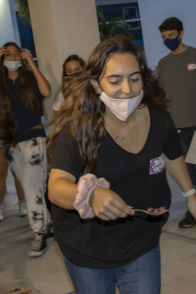 Gena Escanaverino, from St. Brendan High School, participates in one of the events at the Blessed Trinity Life Teen Office Olympics, Sept. 12, 2021.  In this event, teams carried jelly beans on a spoon into bowls. The team who filled their bowl first, won.
