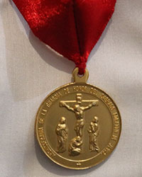 A medal worn by a new member of the Guard of Honor holds the image of the first Guards of Honor, the Blessed Mother, St. John and St. Mary Magdalene. They stood guard at the foot of the cross when Jesus died.