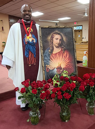 Father Patrick Charles, pastor of St. Stephen Parish in Miramar, displays an image of the Sacred Heart at his parish, which now has a small army of Guards of Honor. He is spiritual director for the parish association.