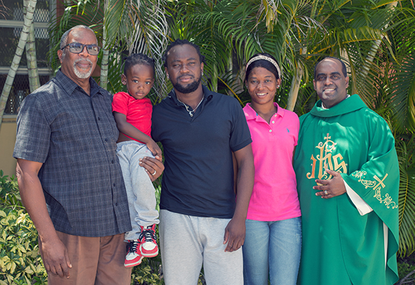 Baliston Elidor, feligrés de Notre Dame d'Haiti (izquierda), sostiene a Kevin-Jay Metellus, de 28 meses, mientras posa para una foto con el padre del niño, Kervens Metellus, y la madre, Marlene Belizaire, y el P. Reginald Jean Mary, párroco de Notre Dame d'Haiti. Elidor acogió a la familia en su casa tras su llegada de Texas, el 26 de septiembre de 2021.