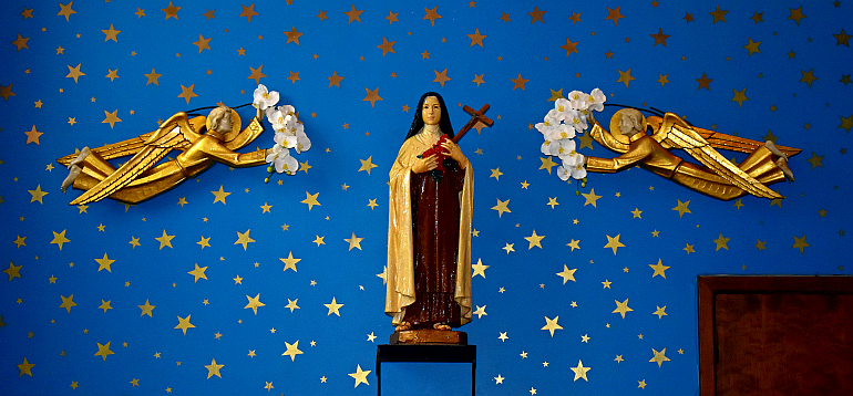 St. Therese of Lisieux, the church's patron, stands in a starry sky with angels offering flowers at Little Flower Church in Hollywood.