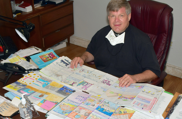 Father Steven O'Hala shows some of the 80 storyboards produced by St. David School students as part of an awareness campaign on the plight of Haiti. "I was blown away," he said.