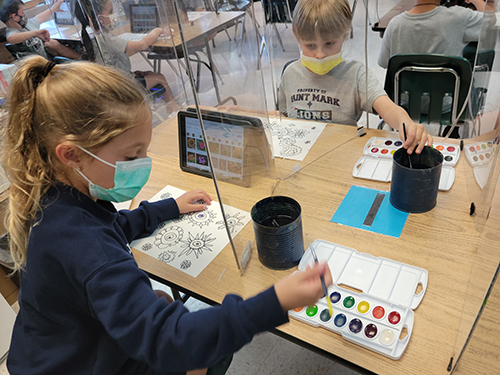 Artistic inspiration and iPads: St. Mark students check in on their color palette and flower styles during a water color lesson. Their art teacher, Carol Powers, incorporates a hands-on water color art lesson with visuals found on student iPads.