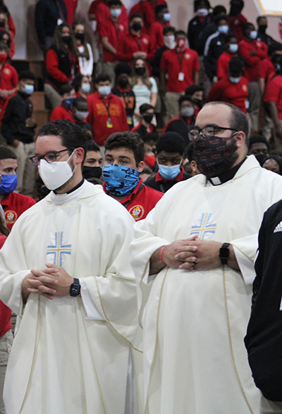 Los sacerdotes y exalumnos de la Escuela Secundaria Msgr. Edward Pace, el P. Bryan García, de la clase de 2006, y el P. Matthew Gómez, de la clase de 2009, procesan hacia el altar durante la Misa por el 60 aniversario de su escuela, el 30 de septiembre de 2021.