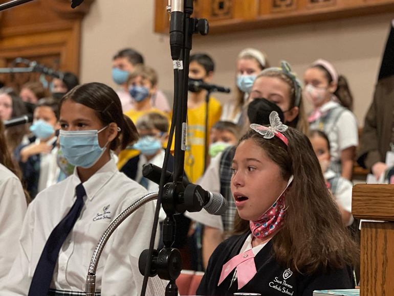 Victoria Biggs and fourth grader Desiree Danger sing in the choir during the school-wide Mass honoring St. Therese at her namesake school in Coral Gables, Oct. 1, 2021.