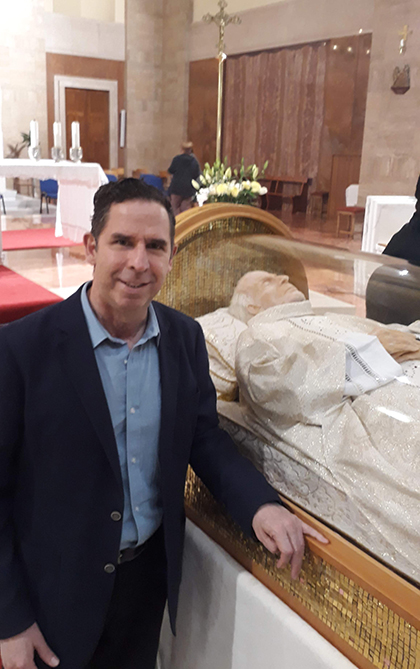 El autor de la nota junto a la urna del beato Santiago Alberione, en su nueva ubicación en la Basílica Reina de los Apóstoles, de Roma.