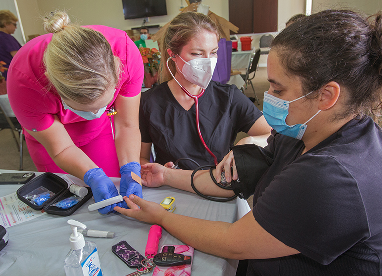 Barry University physician assistant student Makena Fowler administers a glucose test to Sabrina Adams as fellow student Devyn Hale takes her blood pressure during St. Matthew Church's fourth annual Health Fair, Nov. 21, 2021.