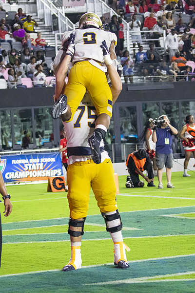 St. Thomas Aquinas tackle Julian Armella (75) lifts up running back Anthony Hankerson (2) in celebration after Hankerson scored the school's six and final touchdown during the Class 7A State Championship game between Aquinas and Tampa Bay Tech at DRV PNK Stadium in Fort Lauderdale, Dec. 17, 2021. Aquinas won the championship with a final score of 42-14.