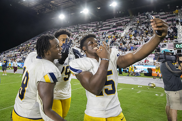 From right, St. Thomas Aquinas defensive lineman Michael Renoit (15) takes a selfie with teammates, tackle Christian Louis-jean (79), and defensive lineman Kyrie Samuel (18), after the team's Class 7A State Championship victory over the Tampa Bay Tech at DRV PNK Stadium in Fort Lauderdale, Dec. 17, 2021.