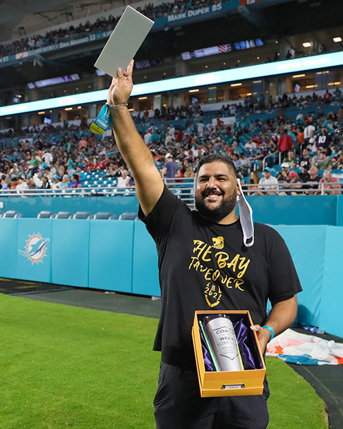 Immaculata-La Salle football coach Helder Valle waves to the crowd after being honored as a Junior Dolphins Coach of the Week during halftime of the New England Patriots game, Jan. 9, 2022 at Hard Rock Stadium. He was one of nine honored as top coaches of the year in South Florida.