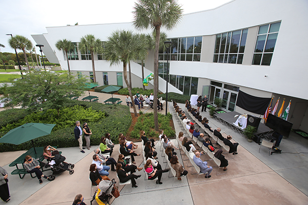 St. Brendan High School board members, administration, student council members, parents, faculty and staff watch a video of Jose Rodelgo-Bueno speaking from Madrid, Spain, during the renaming ceremony for the Innovation Center, also visible at rear, Jan. 12, 2022.