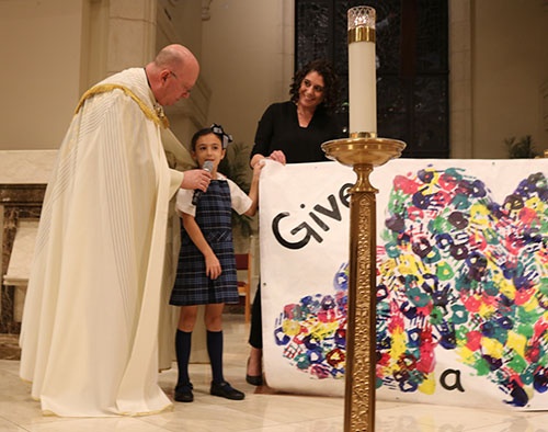 Father Michael Davis, pastor of St. Gregory the Great, talks to Ella Lurig, 7, during the Prayer Service for World Peace at St. Gregory the Great Church Feb. 18, 2022.