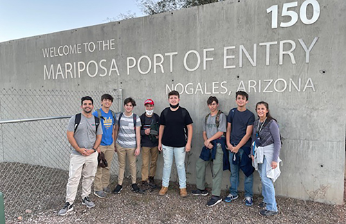 Los estudiantes de la secundaria de Belén y la coordinadora de Servicio Cristiano, Teresita González (derecha), posan frente al puerto de entrada a los Estados Unidos en Nogales, Arizona, durante su viaje en noviembre de 2021 con la Iniciativa Fronteriza de Kino.