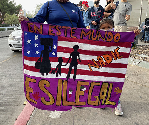 "En este mundo, nadie es ilegal", dice la pancarta que lleva uno de los manifestantes que protestan contra el Título 42, que cierra la frontera a los solicitantes de asilo debido a la pandemia. Los estudiantes de Belén caminaron con los migrantes mientras participaban en la Iniciativa Fronteriza Kino, en noviembre de 2021.