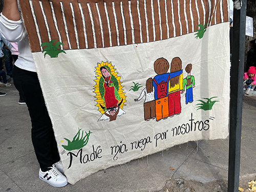 "Madre mía, reza por nosotros", dice el cartel que lleva uno de los manifestantes que protestan contra el Título 42, que cierra la frontera a los solicitantes de asilo por la pandemia. Los estudiantes de Belén caminaron con los migrantes mientras participaban en la Iniciativa Fronteriza Kino, en noviembre de 2021.