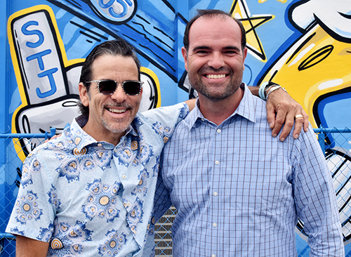 Henry Garcia, left, buddies up with his cousin, Ramiro Inguanzo, after the dedication of the new mural at St. John the Apostle School, March 25, 2022. Both cousins grew up in the school and the neighborhood.