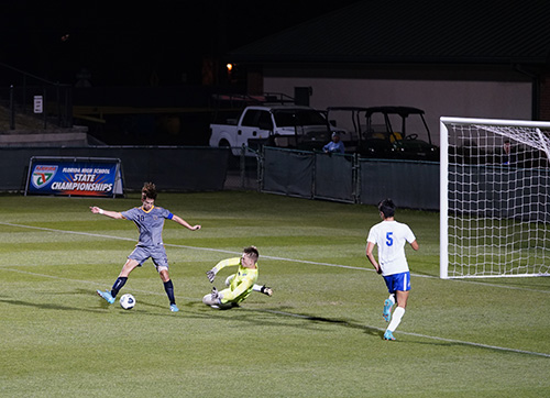 Belen Jesuit's Matias Perinot forces goalkeeper Ryan Laymon to make one of his seven saves during the Wolverines' defense of last year's state championship, a 1-0 defeat of Panama City Beach's Arnold High, Feb. 26, 2022.
