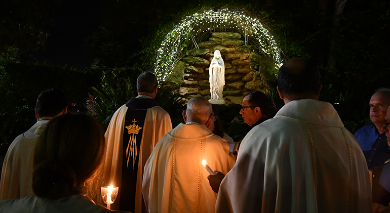 Msgr. Kenneth Schwanger, pastor, leads the faithful in prayer at the grotto on the grounds of Our Lady of  Lourdes in Miami during one of the parish's processions on the 11th of each month.