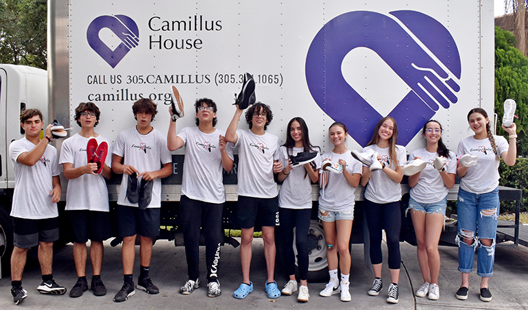 Loving Soles volunteers show off a few of the 12,000 pairs of shoes they rounded up for Camillus House this year.