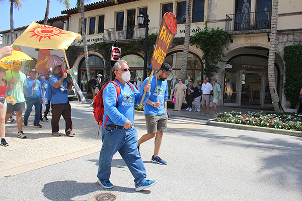 Residents and visitors of Palm Beach watch as Farmworkers with the Coalition of Immokalee Workers and supporters peacefully march in the streets April 2, 2022 to bring awareness to abuse in the fields.
