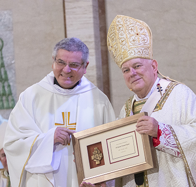 Father Fernando Orejuela, Asociación de la Inmaculada Concepción, receives a plaque from Archbishop Thomas Wenski commemorating his 25 years of priesthood, April 12, 2022.