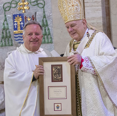 Father Juan Sosa receives a plaque from Archbishop Thomas Wenski commemorating his 50 years of priesthood, April 12, 2022.