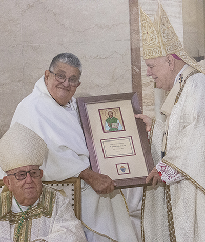 Jesuit Father Pedro Suarez receives a plaque from Archbishop Thomas Wenski commemorating his 50 years of priesthood, April 12, 2022.