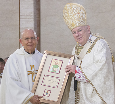 Jesuit Father Eduardo Barrios receives a plaque from Archbishop Thomas Wenski commemorating his 50 years of priesthood, April 12, 2022.