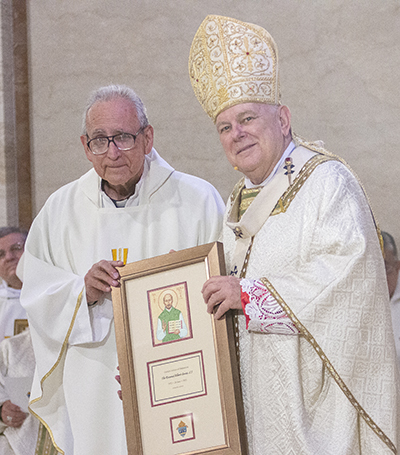 Jesuit Father Alberto Garcia receives a plaque from Archbishop Thomas Wenski commemorating his 50 years of priesthood, April 12, 2022.