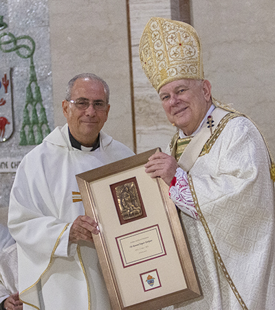 Father Joaquin Rodriguez receives a plaque from Archbishop Thomas Wenski commemorating his 50 years of priesthood, April 12, 2022.