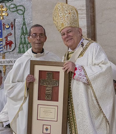 Father Jose Luis Paniagua receives a plaque from Archbishop Thomas Wenski commemorating his 60 years of priesthood, April 12, 2022.