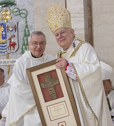 Father Juan Lopez receives a plaque from Archbishop Thomas Wenski commemorating his 60 years of priesthood, April 12, 2022.