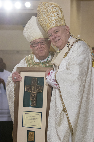 Archbishop emeritus John C. Favalora presents his successor, Archbishop Thomas Wenski, with a plaque commemorating his 25th anniversary as a bishop during the chrism Mass, April 12, 2022.