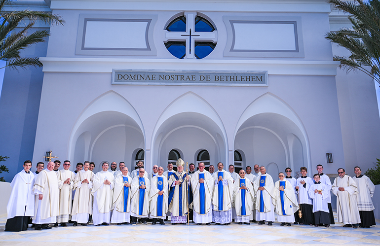 Los sacerdotes jesuitas, diáconos y estudiantes que sirvieron en la Misa de dedicación posan junto al Arzobispo Thomas Wenski frente a la nueva capilla de más de 600 asientos del Colegio de Belén, el 1 de mayo de 2022.