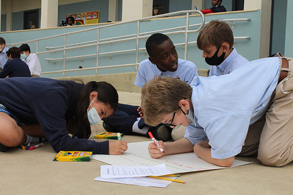 Fifth graders Abigail Perez-Pinon and Jeremiah Petit-Homme from St. Mary's Cathedral School work with Nick Garciga and Sebastian Grau from St. Louis Covenant School decorating and lettering their Precept Poster. Students from both schools gathered on March 17, 2022 for "We Are All God's Wonder Day" at St. Mary's. After reading "Wonder" by R.J. Palacio together, but from a distance, students from both schools shared a day of fellowship with activities revolving around the novel and getting to know each other better.