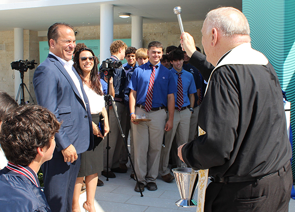 Archbishop Thomas Wenski blesses donors Mario Sueiras and his wife Sandra, along with students, faculty, and guests, with holy water during the inauguration of the new Marcus Lemonis and Mario Sueiras Center for Science and the Arts building at Christopher Columbus High School on April 28, 2022.