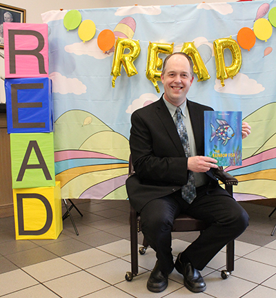 Archdiocese of Miami Superintendent of Schools Jim Rigg holds up "The Rainbow Fish" by Marcus Pfister, which he read to students from Blessed Trinity School in Miami Springs on April 29, 2022. His visit and reading concluded the Enchanted Book Fair, a week-long literary celebration at the school.