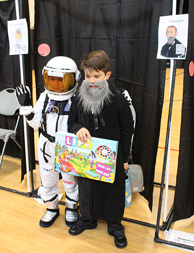 One last game before you jet off: Astronaut Neil Armstrong, portrayed by Raul Planas, and game pioneer Milton Bradley, portrayed by Elias Planas, pose for a photo at the Third Grade Wax Museum at St. Louis Covenant School in Pinecrest, April 29, 2022, in the school's gym-auditorium.