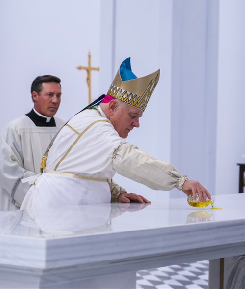 Archbishop Thomas Wenski pours oil of chrism on the altar of Our Lady of Belen Chapel during the blessing and dedication Mass, May 1, 2022. The 600-seat chapel is located on the grounds of Belen Jesuit Prep in Miami. Behind him is Father Richard Vigoa, pastor of St. Augustine Church and Catholic Student Center in Coral Gables and director of the archdiocesan Office of Worship.