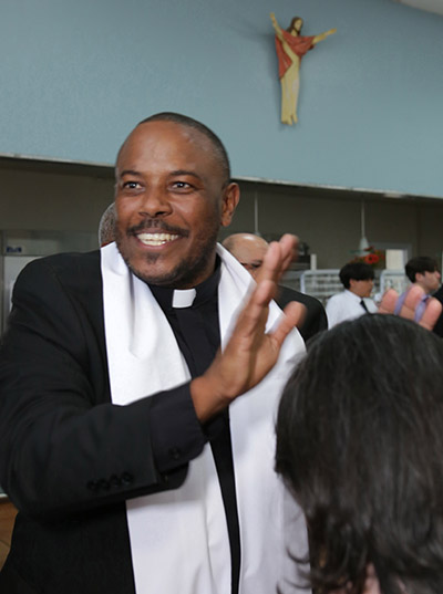 El recién ordenado P. César Betancourt ríe antes de dar su bendición a un asistente de la ceremonia, después de su ordenación, el 7 de mayo de 2022, en la Catedral St. Mary.