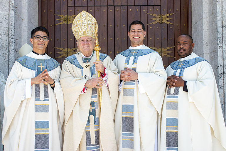Delante de Catedral St. Mary, los recién ordenados sacerdotes posan para sus fotos oficiales con el Arzobispo Thomas Wenski. Desde la izquierda, el P. Agustín Estrada, el P. Enzo Prendes y el P. César Betancourt, el 7 de mayo de 2022.