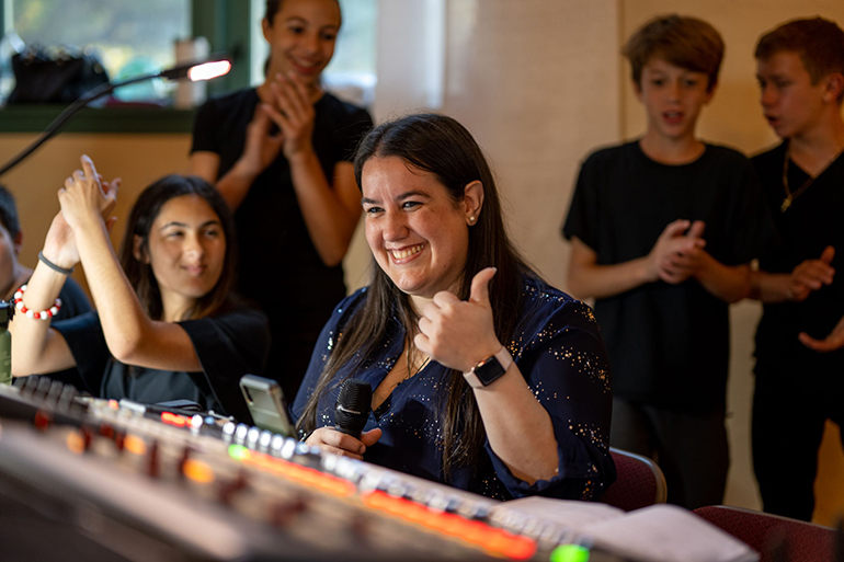 Surrounded by students, Rosa Fiol, the musicalâ€™s director and St. Theresa music teacher, makes sure all is well at the sound board during the school's production of the Disney musical Beauty and the Beast. The play was staged May 6 and 7, 2022.
