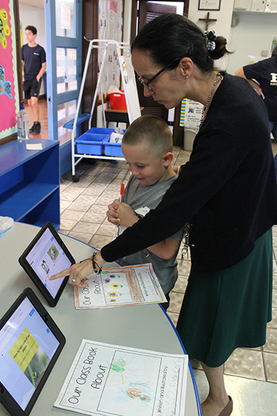 Little Flower School Principal Omayra Roy flips through the e-book "How To Take Care of a Plant" with a student during the STEM Academic Showcase at the Hollywood school on May 18, 2022. Family and friends came to look at a variety of exhibits created by students.