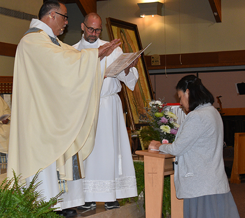 El P. Pedro Corces bendice a la Hna. Lizeth Guadalupe Manrique Músico antes de ella hacer su profesión perpetua como Misionera Claretiana, el 31 de mayo de 2022 en la iglesia St. Timothy en Miami.