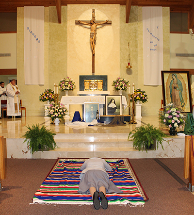 La Hna. Lizeth Guadalupe Manrique Músico se postra mientras la congregación reza la letanía de los santos durante el rito que marcó su profesión perpetua como misionera claretiana, el 31 de mayo de 2022 en la iglesia St. Timothy en Miami.