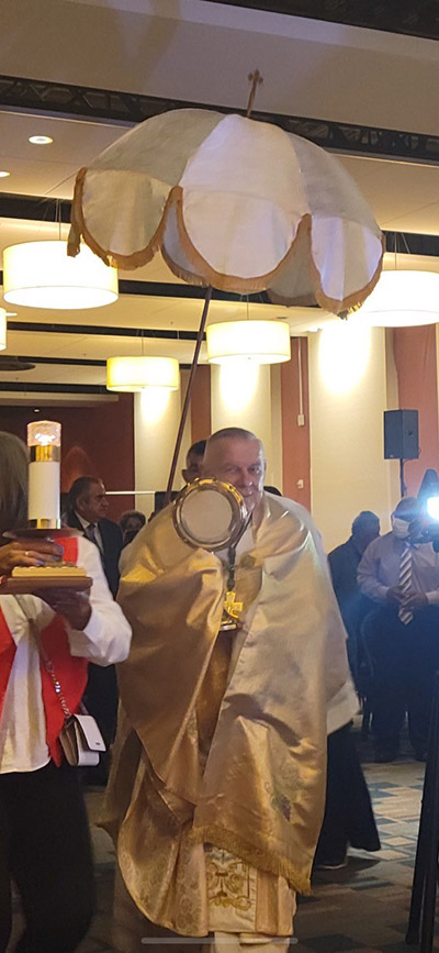 Archbishop Thomas Wenski carries the Blessed Sacrament in procession through the hall at the Miami Airport Convention Center where Hispanic charismatics from across the Archdiocese of Miami held their 37th annual conference, June 18 and 19, 2022. The procession took place after the closing Mass, celebrated by the archbishop.
