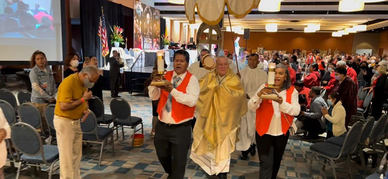 Archbishop Thomas Wenski carries the Blessed Sacrament in procession through the hall at the Miami Airport Convention Center where Hispanic charismatics from across the Archdiocese of Miami held their 37th annual conference, June 18 and 19, 2022. The procession took place after the closing Mass, celebrated by the archbishop.